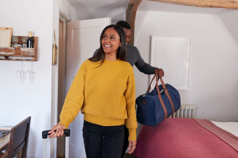 Young woman arriving at her new home with a bag